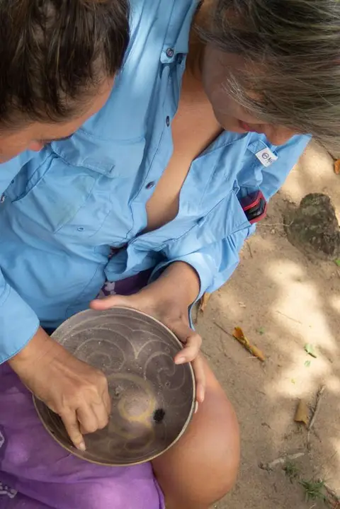 A carved calabash bowl.. Silicia tries her hand at sanding a carved bowl using a 'sandpaper leaf'.